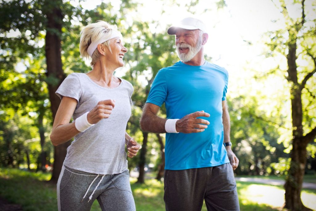 Active senior couple jogging in a park, embodying holistic relief from neuropathy and chronic pain.